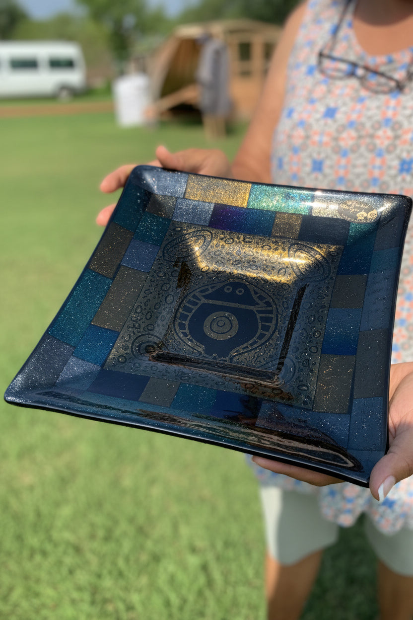 May Rosas holding a decorative blue and gold  glass platter outdoors by Diganbal Designs.